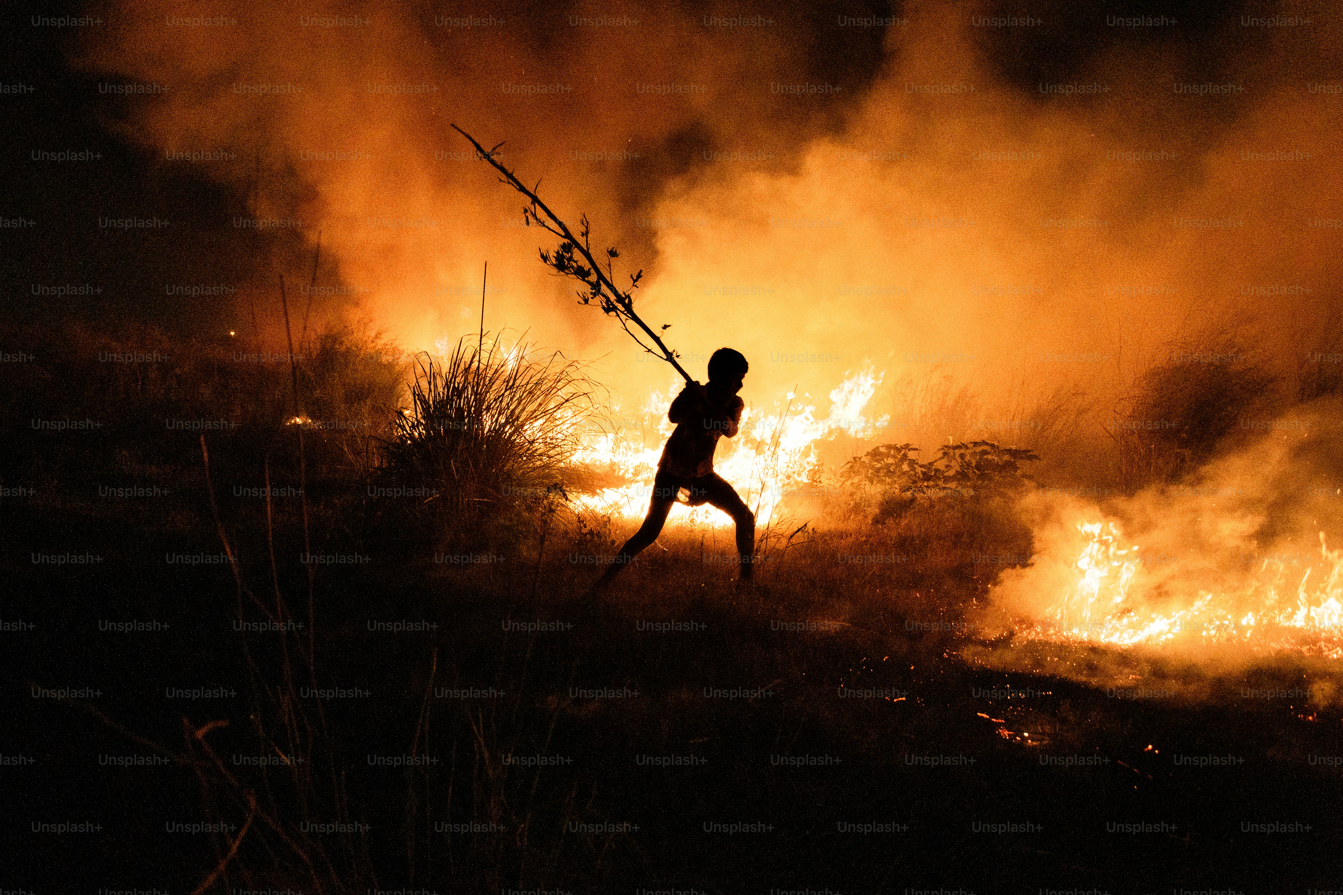 A person running through a field with a fire in the background